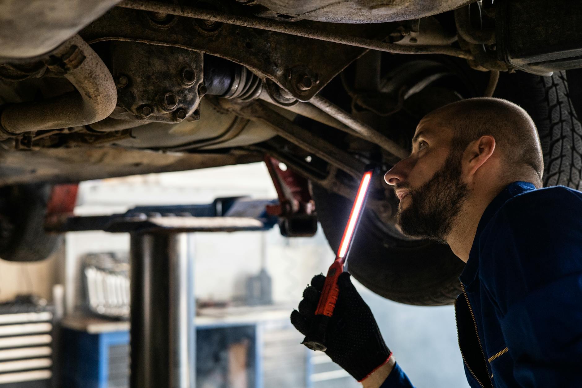 Mechanik z latarką sprawdza podwozie auta w warsztacie